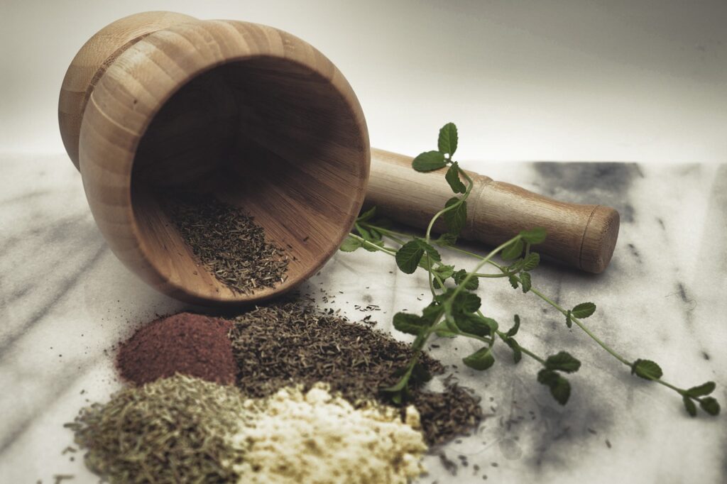 Wooden crushing bowl with crushed herbs, symbolizing the preparation of natural remedies using herbal products for health and wellness